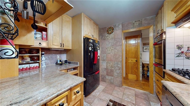 kitchen with tile walls, light stone countertops, black appliances, and light brown cabinets