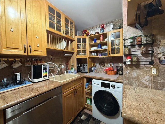 kitchen featuring sink, dishwasher, light stone counters, washer / clothes dryer, and decorative backsplash