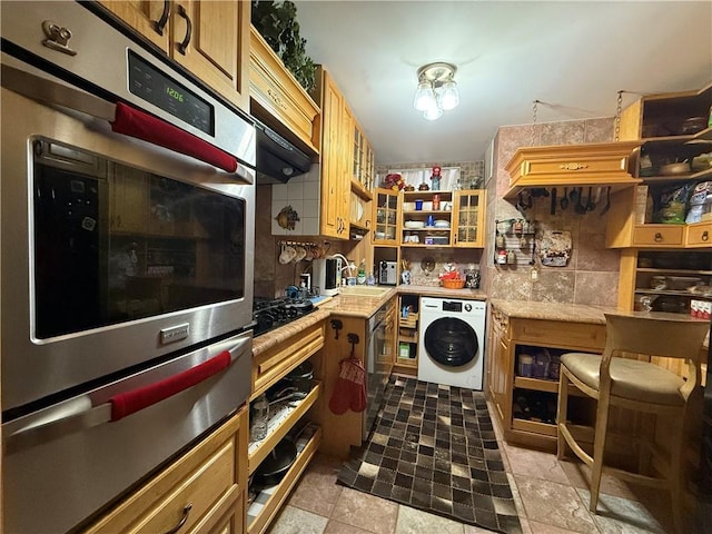 kitchen featuring sink, black gas cooktop, decorative backsplash, washer / dryer, and oven