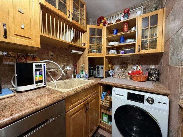 clothes washing area with washer / clothes dryer, sink, and cabinets