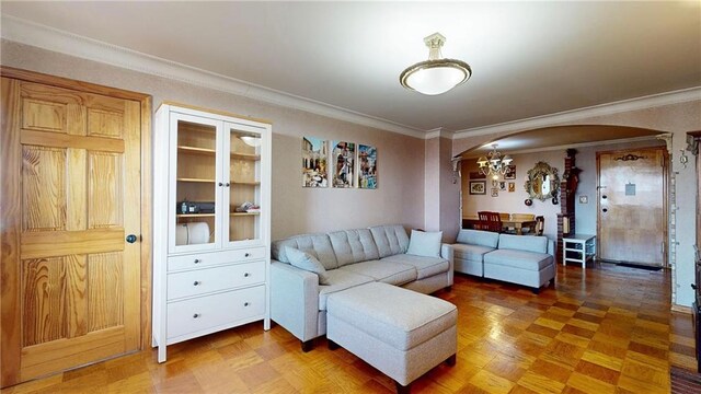 living room with crown molding, parquet floors, and a notable chandelier