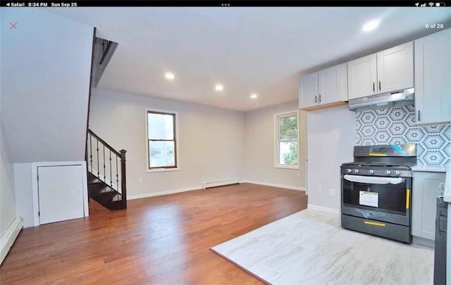 kitchen with a baseboard radiator, stainless steel gas range, light hardwood / wood-style floors, decorative backsplash, and white cabinets