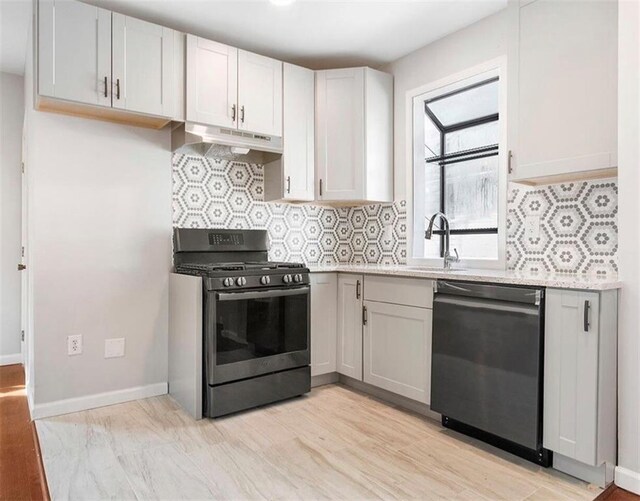 kitchen featuring decorative backsplash, appliances with stainless steel finishes, light wood-type flooring, sink, and white cabinetry