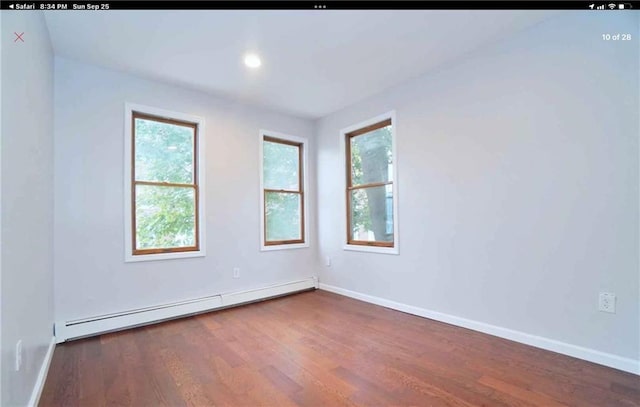 empty room with dark hardwood / wood-style flooring and a baseboard heating unit