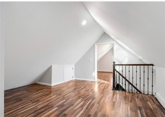 additional living space with dark hardwood / wood-style floors, vaulted ceiling, and a baseboard radiator