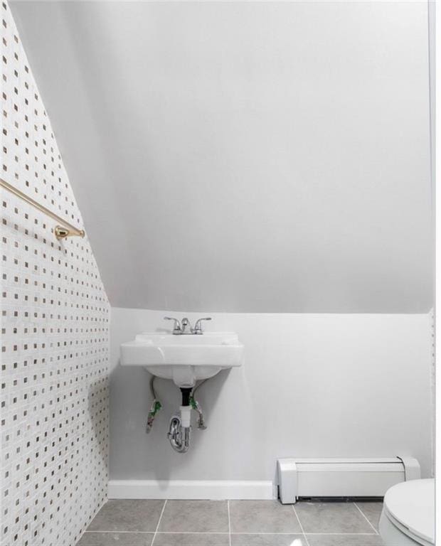 bathroom featuring tile patterned flooring, vaulted ceiling, and a baseboard heating unit