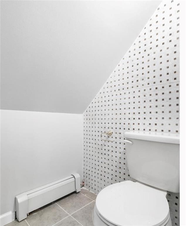 bathroom with toilet, tile patterned flooring, vaulted ceiling, and a baseboard heating unit