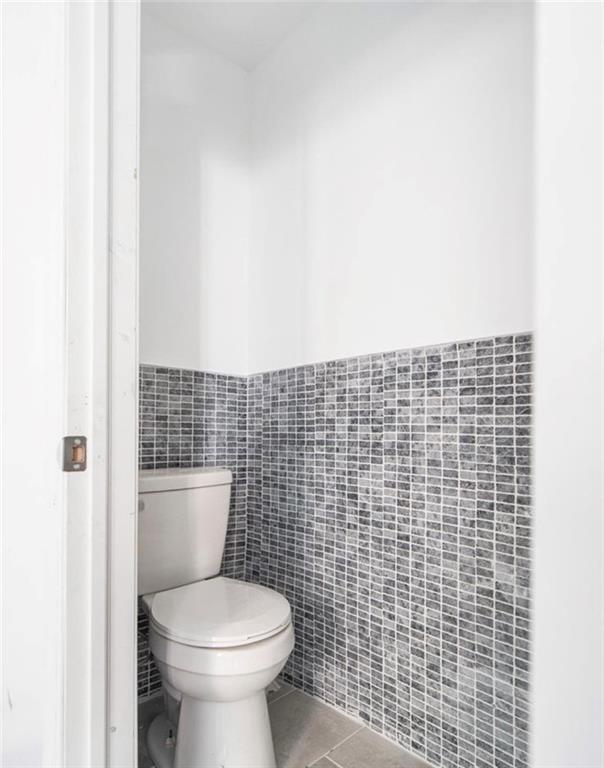 bathroom featuring tile patterned floors, tile walls, and toilet