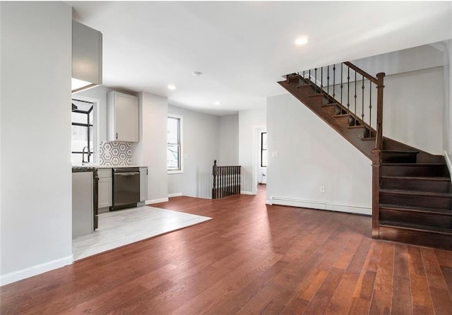 unfurnished living room with dark hardwood / wood-style floors, sink, and baseboard heating