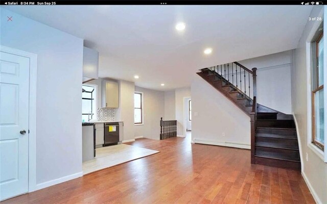 unfurnished living room with light hardwood / wood-style flooring and a baseboard heating unit