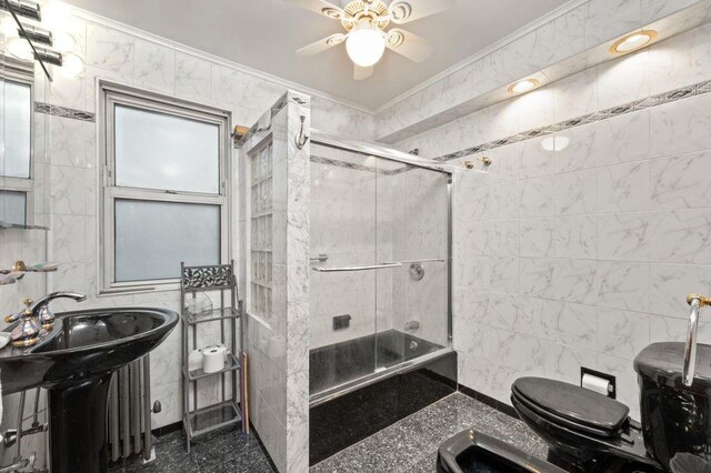 full bathroom with toilet, sink, crown molding, bath / shower combo with glass door, and tile walls