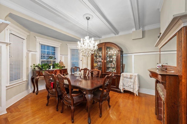 dining space featuring beamed ceiling, ornamental molding, light hardwood / wood-style floors, and a notable chandelier