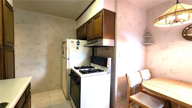 kitchen featuring white range with gas stovetop, light tile patterned floors, under cabinet range hood, and wallpapered walls