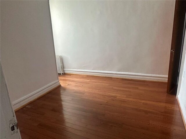 empty room with radiator and dark hardwood / wood-style flooring