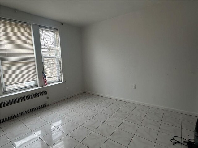 spare room featuring radiator heating unit and light tile patterned floors