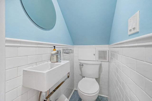 bathroom featuring toilet, tile walls, and sink