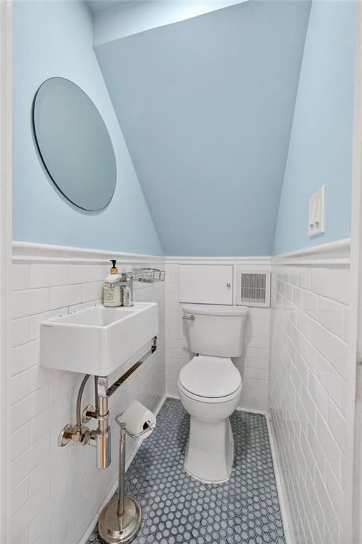 bathroom featuring toilet, sink, tile walls, and tile patterned floors