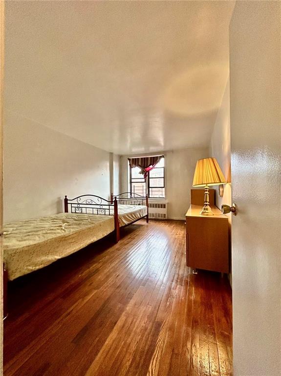 bedroom with radiator and dark wood-type flooring