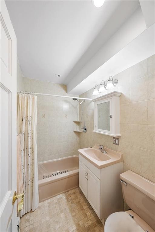 full bath featuring toilet, shower / bathtub combination with curtain, tile walls, and vanity