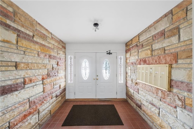 tiled foyer featuring brick wall and mail boxes