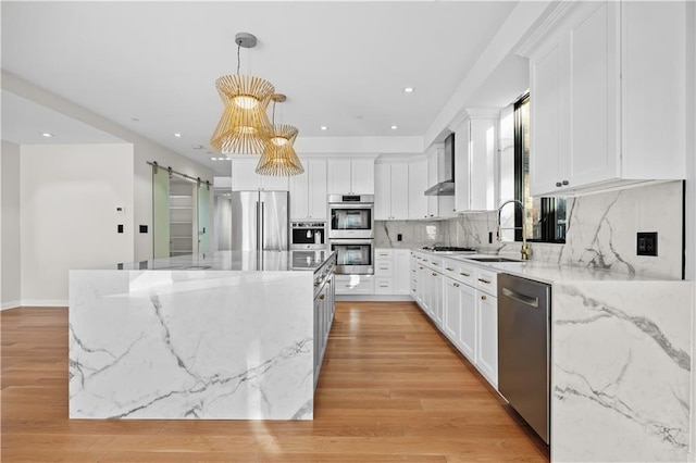 kitchen with tasteful backsplash, a barn door, a kitchen island, stainless steel appliances, and a sink