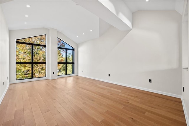 unfurnished living room with light wood-style floors, lofted ceiling, and baseboards