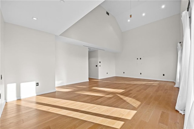 interior space with high vaulted ceiling, light wood-type flooring, and baseboards