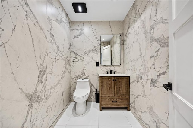 bathroom with vanity, toilet, and stone wall