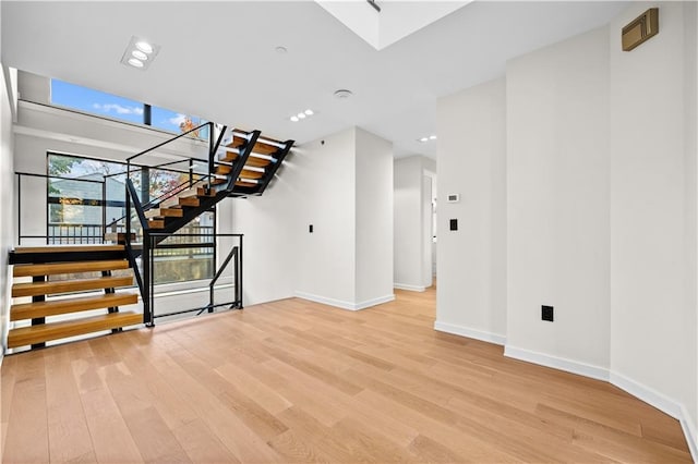 unfurnished living room featuring baseboards, stairway, and wood finished floors