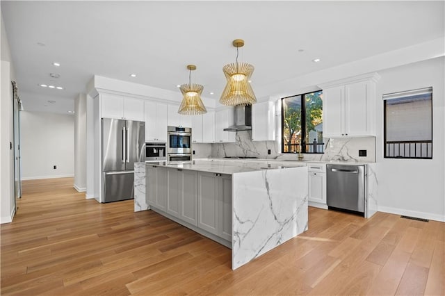 kitchen with stainless steel appliances, wall chimney range hood, backsplash, and white cabinets