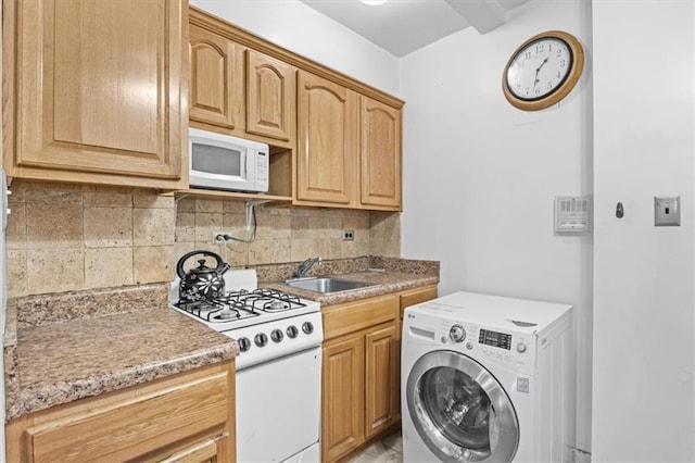 kitchen featuring white appliances, washer / dryer, decorative backsplash, light countertops, and a sink