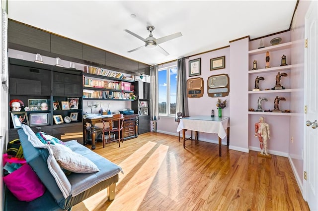 living area with ceiling fan, built in features, and light hardwood / wood-style floors