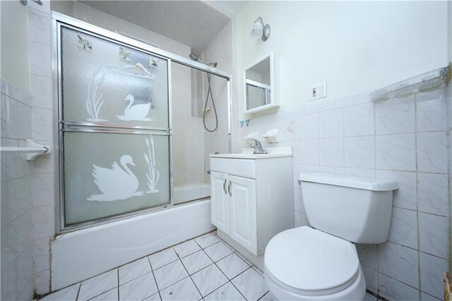 full bathroom with vanity, tile walls, toilet, and combined bath / shower with glass door