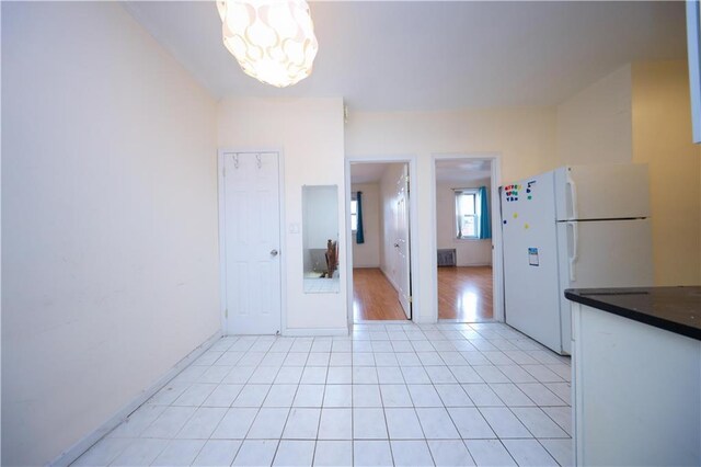 kitchen with light tile patterned flooring, a chandelier, and white fridge