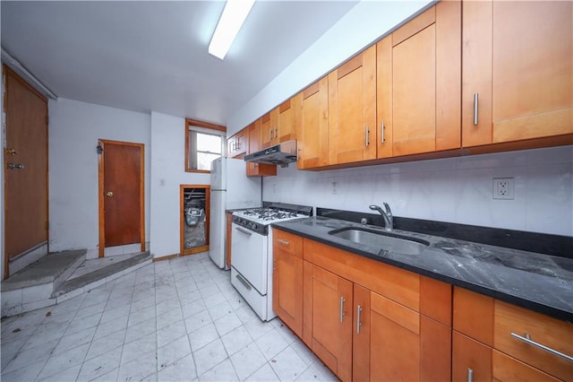 kitchen with sink, dark stone countertops, and white appliances