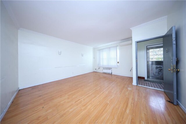 unfurnished living room featuring ornamental molding, radiator heating unit, and light hardwood / wood-style flooring