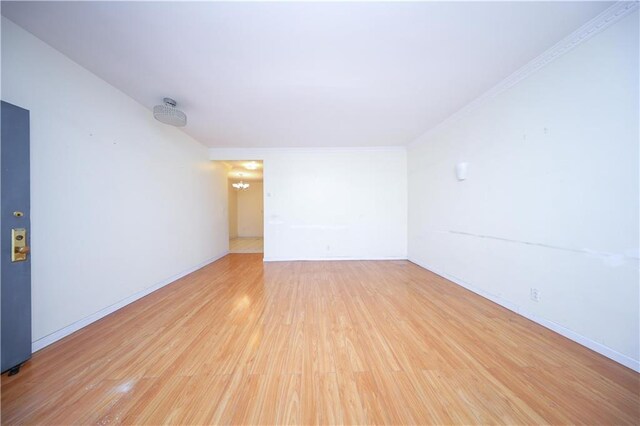 spare room with ornamental molding, light hardwood / wood-style flooring, and a notable chandelier