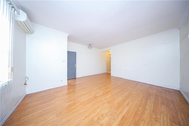 spare room featuring light hardwood / wood-style flooring, ornamental molding, and an AC wall unit