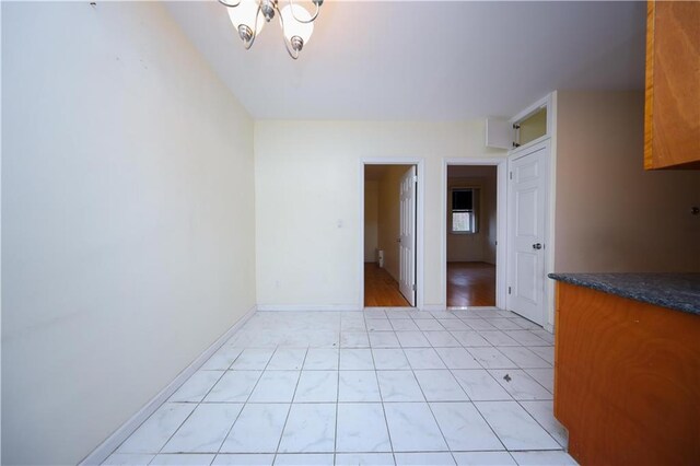 unfurnished room featuring a chandelier