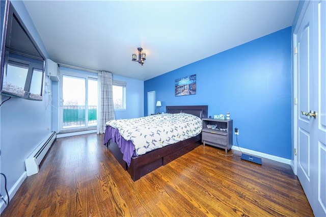 bedroom featuring a baseboard heating unit, wood finished floors, and baseboards