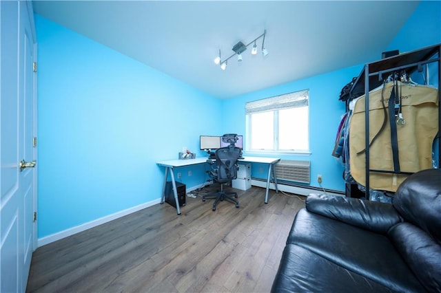 home office with rail lighting, baseboards, baseboard heating, and wood finished floors