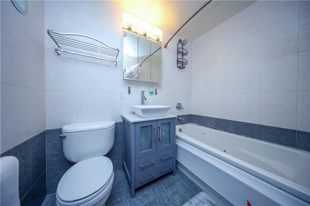 bathroom with tile walls, toilet, vanity, a bath, and tile patterned floors