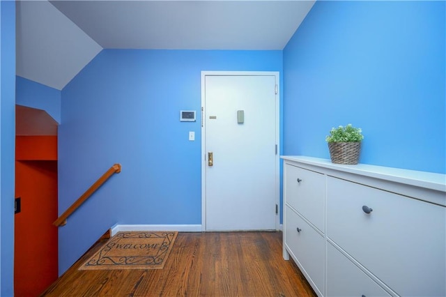 interior space with lofted ceiling, baseboards, arched walkways, and dark wood-type flooring