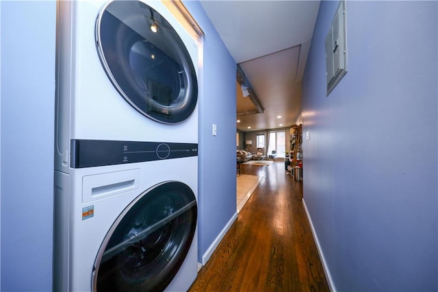 washroom with recessed lighting, stacked washing maching and dryer, wood finished floors, laundry area, and baseboards