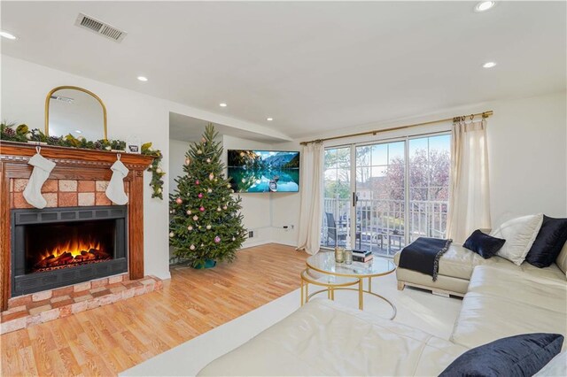 living room featuring a tile fireplace, lofted ceiling, and hardwood / wood-style flooring