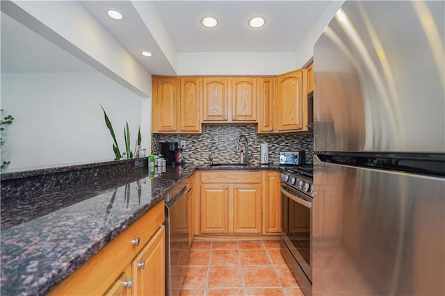 kitchen with stainless steel appliances, dark stone countertops, sink, backsplash, and light tile patterned floors