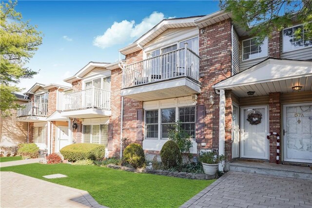 view of property with a balcony and a front lawn