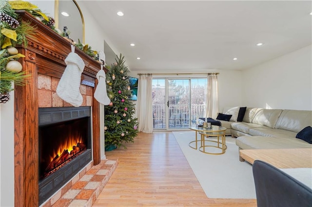 living room with a tile fireplace and light wood-type flooring