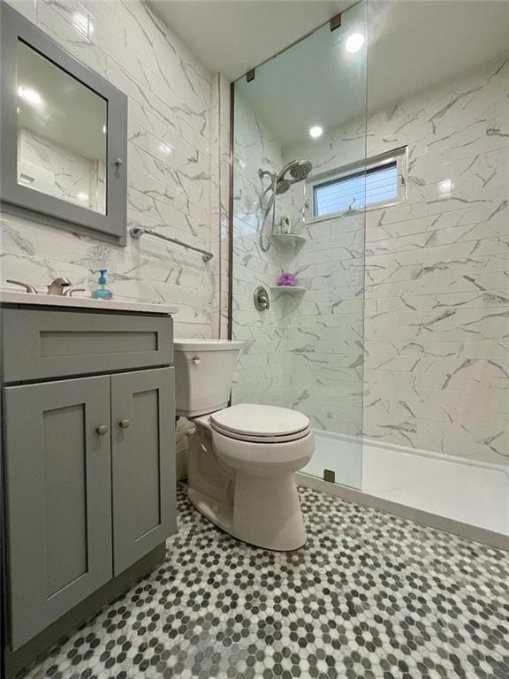 full bath with toilet, walk in shower, tile walls, and vanity