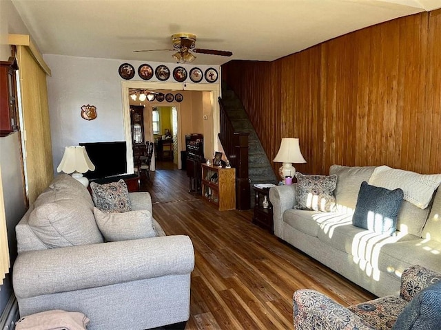 living area featuring dark wood-type flooring, ceiling fan, and stairs